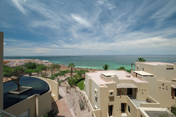 A coastal hotel with a pool, palm trees, and a view of the sea. - Puerta Cortés Residences by Lumina (La Paz)