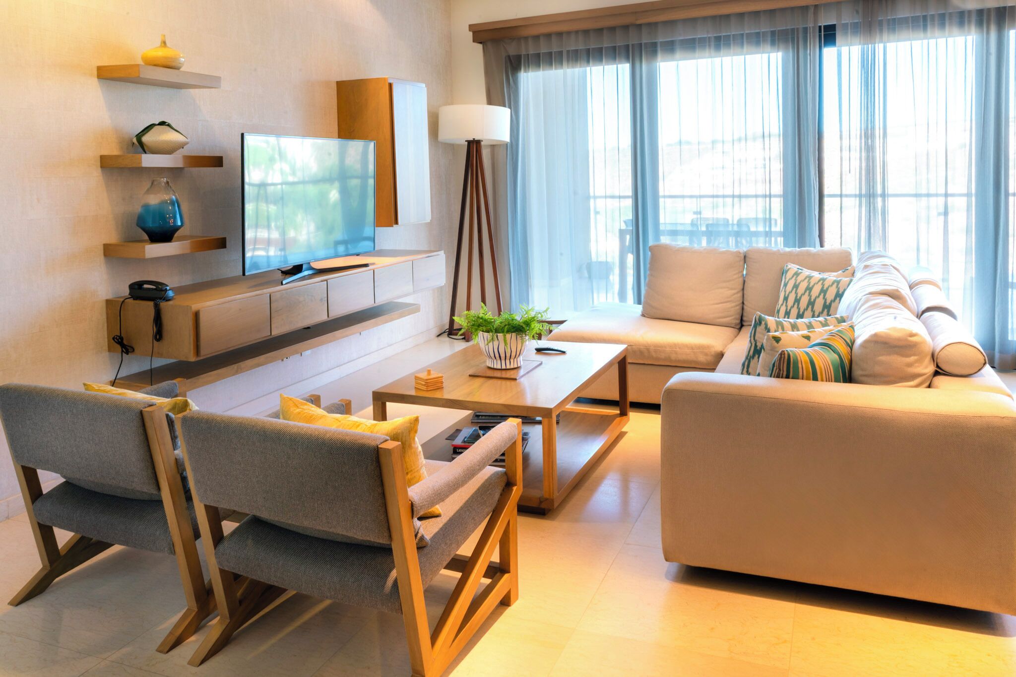 Una sala de estar moderna con sofá, mesa de centro, televisor y lámpara.
