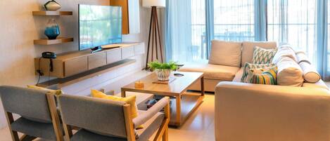 Una sala de estar moderna con sofá, mesa de centro, televisor y lámpara.