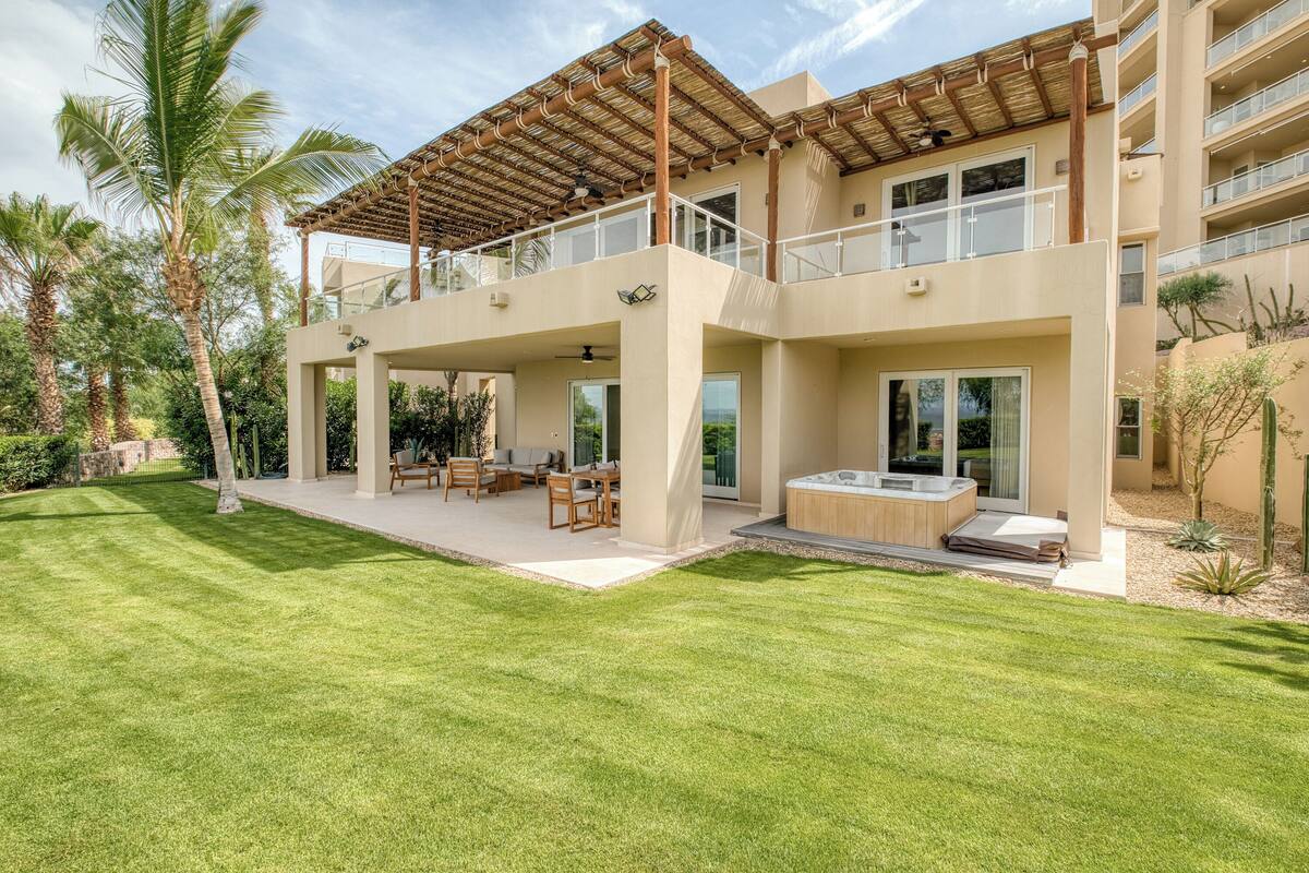 A modern two-story building with a covered patio, outdoor seating area, and a hot tub.