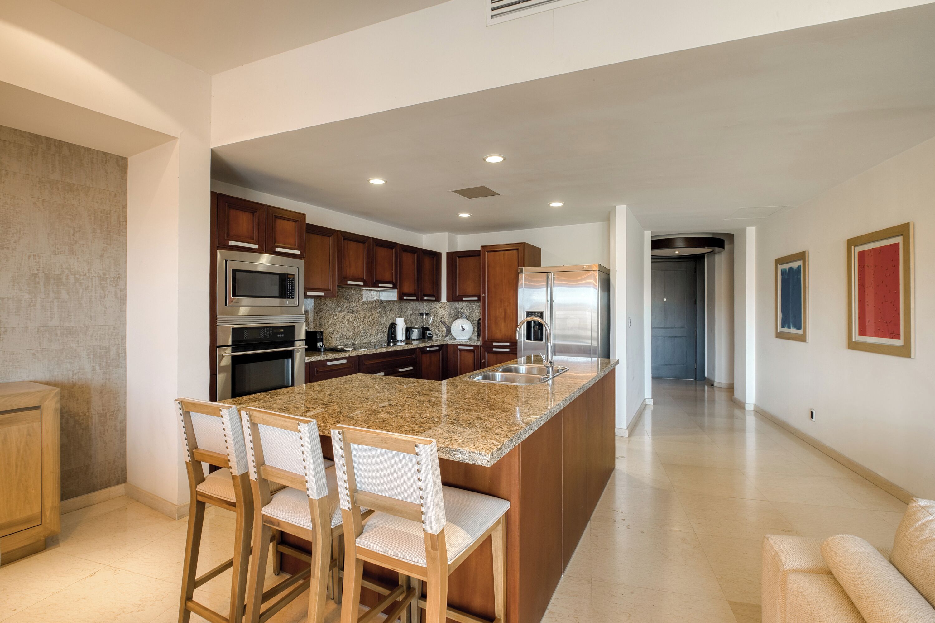 Una cocina moderna con encimeras de granito, electrodomésticos de acero inoxidable y armarios de madera.