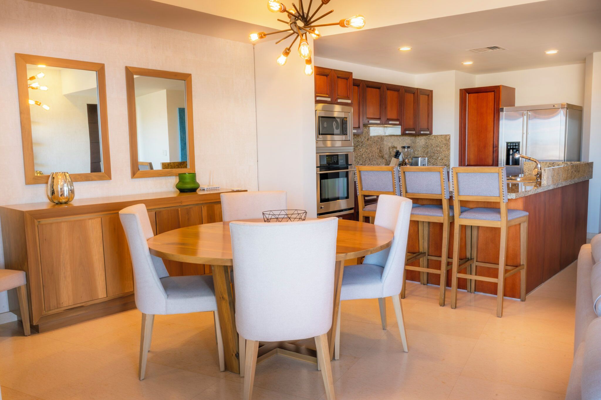 A modern kitchen with wooden cabinets, stainless steel appliances, and a dining area with a round table and white chairs.