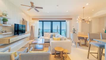 A modern living room with a television, sofa, dining area, and large windows with a view.