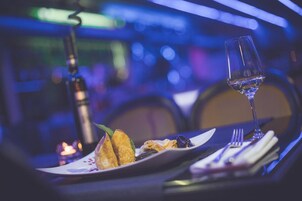 Una mesa dispuesta con una copa de vino, un plato de comida y una vela, evocando un ambiente para cenar.