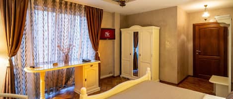Habitación de hotel con cama, escritorio con teléfono, armario y puerta.