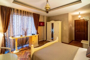 Habitación de hotel con cama, escritorio con teléfono, armario y puerta.