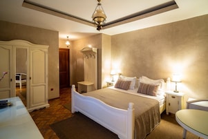 Un dormitorio con cama, mesitas de noche, armario y perchero.