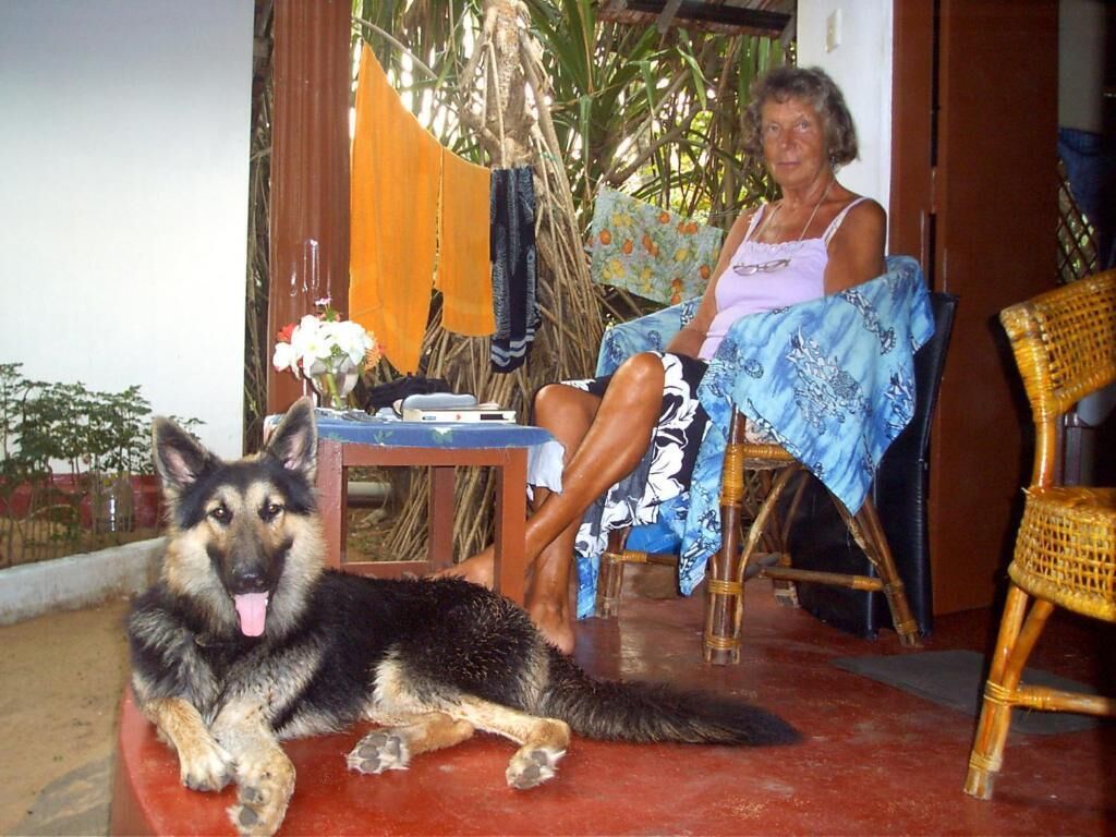 Una habitación con piso rojo, una mesa con un jarrón de flores y una silla.