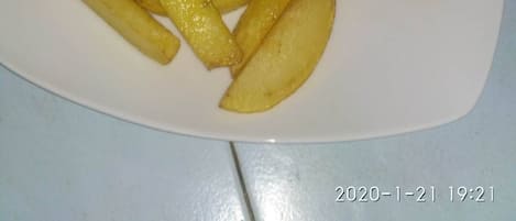 A plate with a cooked fish, fries, and a lime wedge.