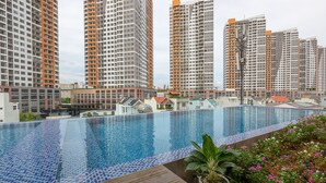 Une piscine dont le bord est revêtu de carrelage, entourée d’immeubles d’habitation de grande hauteur.