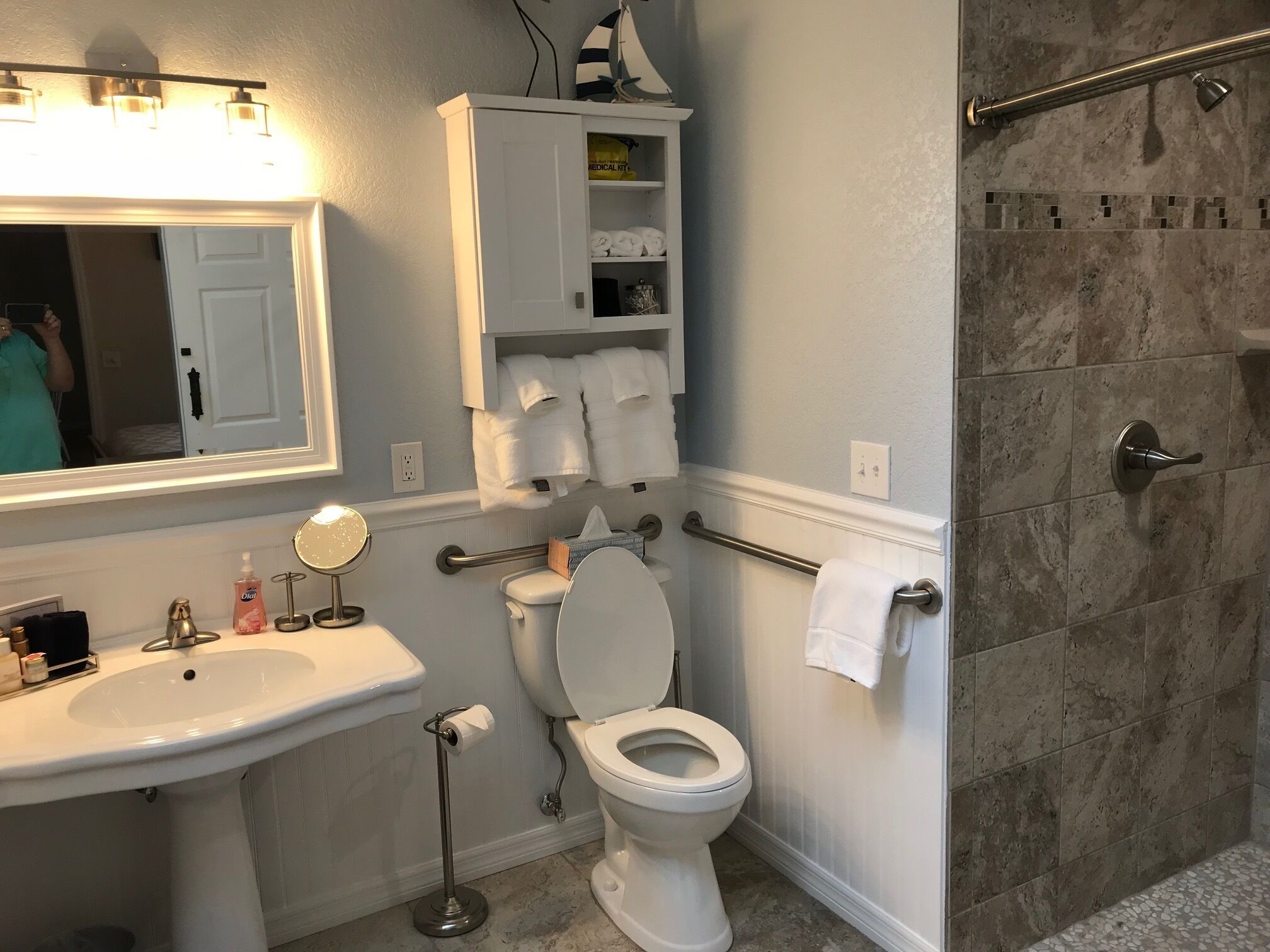 Un baño con lavamanos blanco, inodoro, zona de ducha y espejo.