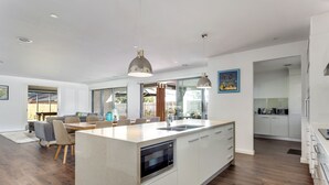 Et moderne køkken med en central ø, hvide skabe og en indbygget ovn.