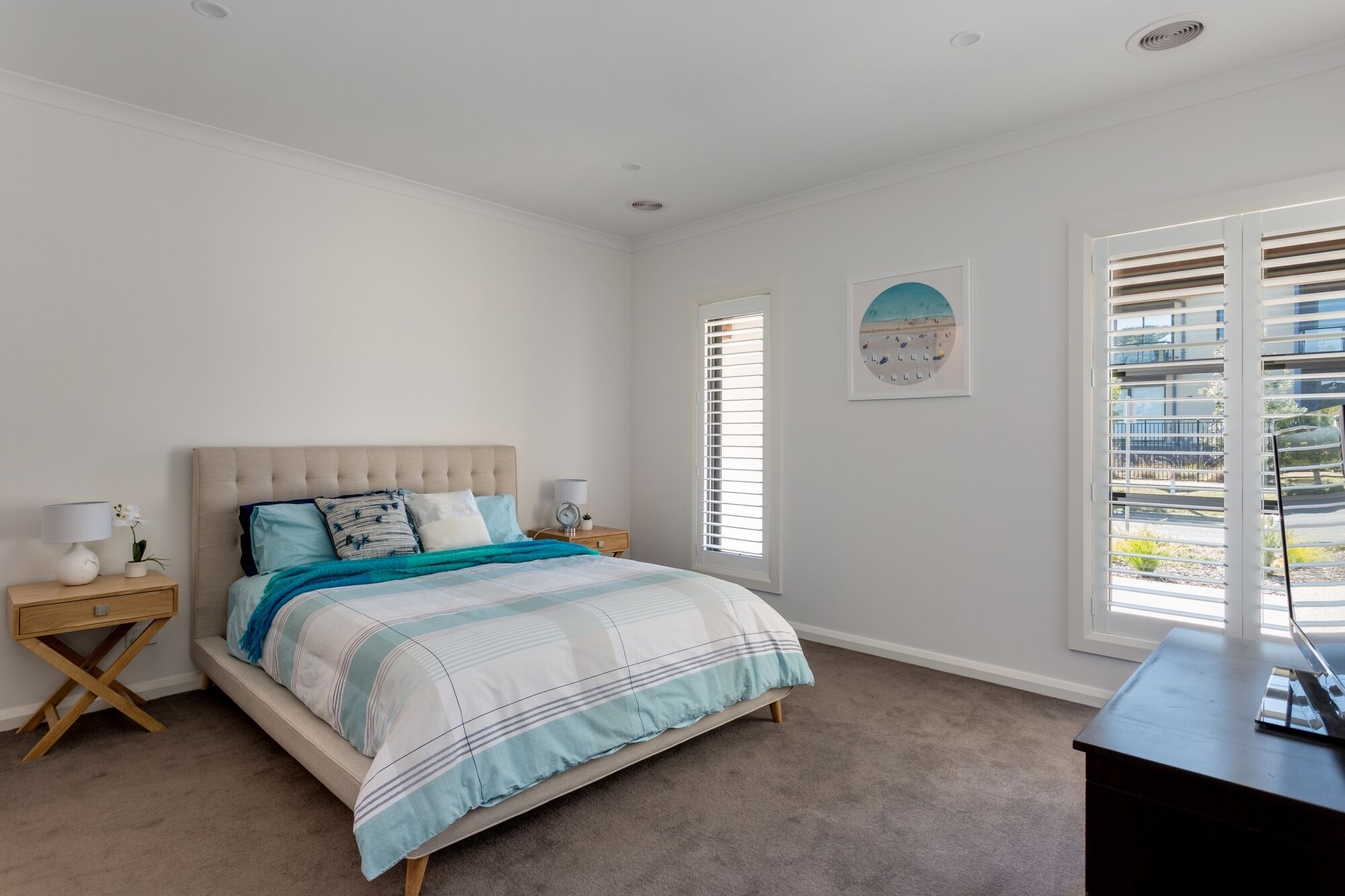 A bedroom with a bed, nightstands, a dresser, and a window with blinds.