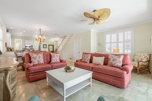 A spacious living room with two red sofas, a white coffee table, and a ceiling fan.