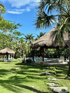 A resort with thatched-roof structures, outdoor seating, and a pool area.