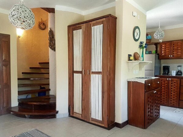 A kitchen with wooden cabinets, a clock, and a shelf with decorative items.