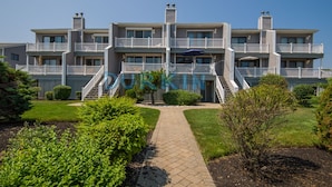 A multi-story hotel with balconies, a central entrance, and a landscaped garden.