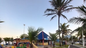 A playground with colorful play structures and a blue-roofed building in the background. - Country house/farm in Peruíbe with adult and children's swimming pool, sauna and hot tub. (Estância Antonio Novaes)