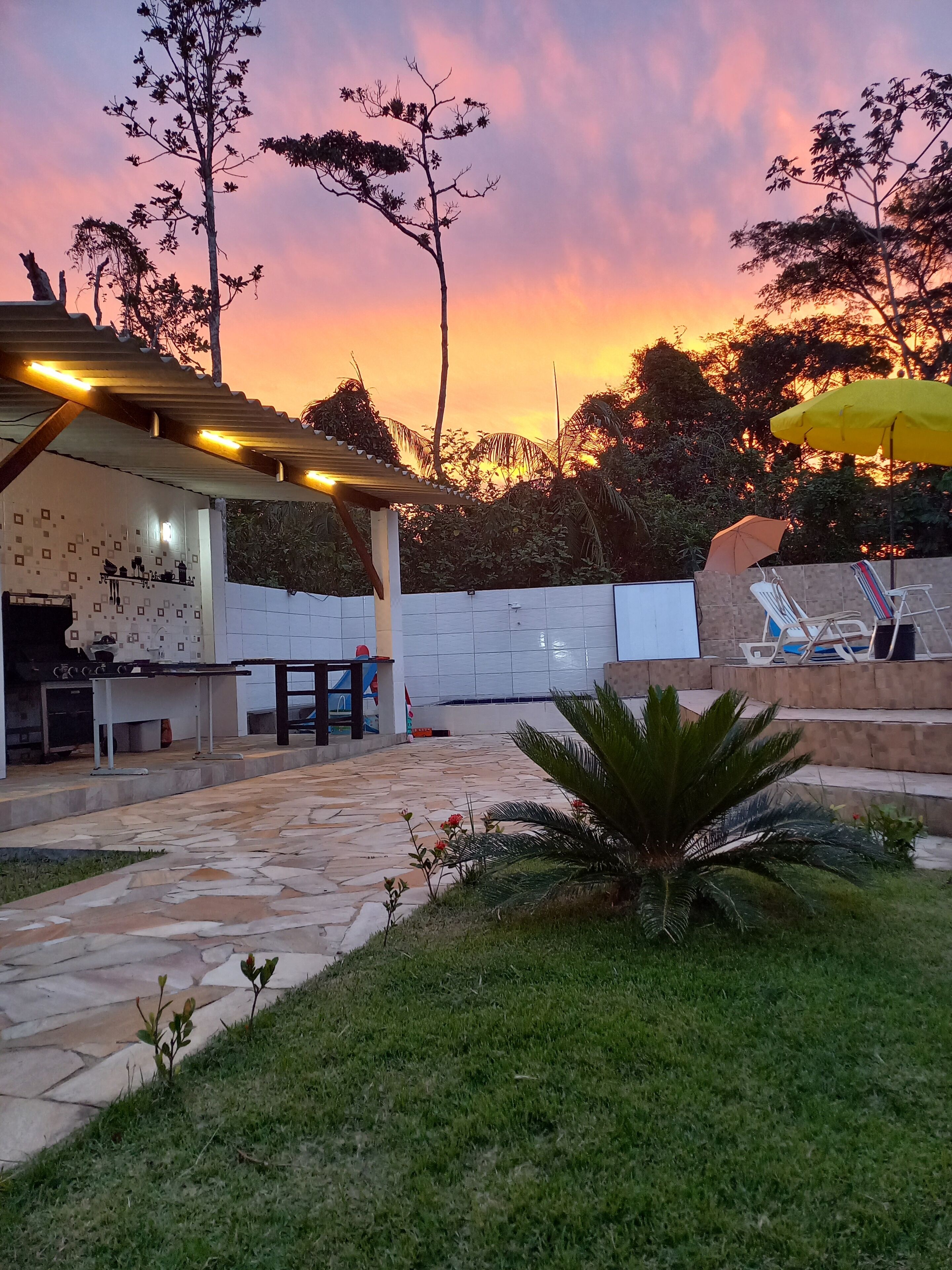 A patio area with a stone floor, outdoor seating, and a pergola with string lights.