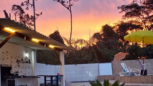 A patio area with a stone floor, outdoor seating, and a pergola with string lights. - Country house/farm in Peruíbe with adult and children's swimming pool, sauna and hot tub. (Estância Antonio Novaes)