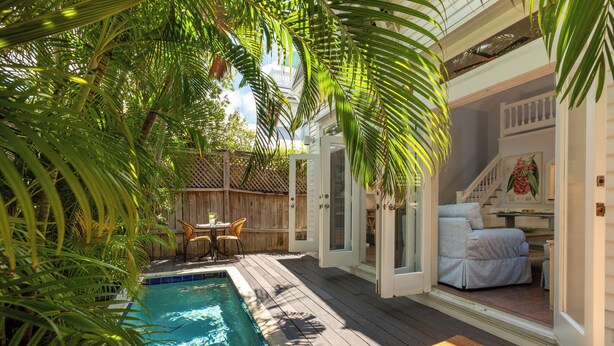A pool area with a wooden deck, a lounge chair, and a small table. - CONCH HEAVEN ~ Stylish 2B/2Ba, Sleeps 6 in Old Town w/ Heated Cocktail Pool! (Key West)
