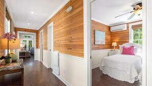 A bedroom with a wooden wall, a white bed, and a ceiling fan. - CONCH HEAVEN ~ Stylish 2B/2Ba, Sleeps 6 in Old Town w/ Heated Cocktail Pool! (Key West)