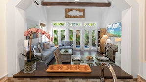 A spacious living area with a dining table, sofas, and a ceiling fan. - CONCH HEAVEN ~ Stylish 2B/2Ba, Sleeps 6 in Old Town w/ Heated Cocktail Pool! (Key West)