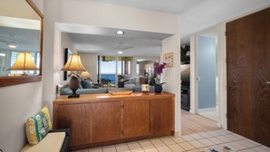 A spacious living area with a wooden cabinet, a bench, and a view to the outside. - Full Ocean View, Great For Whale Watching (Princeville)