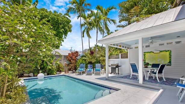 A swimming pool with lounge chairs and a covered patio area. - MANGO MARGARITA~ 2 bedroom/2.5 bath, heated private pool, and close to Duval! (Key West)