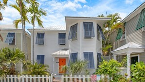 A two-story house with a white exterior, blue shutters, and a red door. - MANGO MARGARITA~ 2 bedroom/2.5 bath, heated private pool, and close to Duval! (Key West)