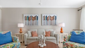 A living room with a sofa set, two side tables with lamps, and two wall-mounted paintings. - MANGO MARGARITA~ 2 bedroom/2.5 bath, heated private pool, and close to Duval! (Key West)