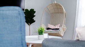Een gezellige woonkamer met een hangstoel, een witte tafel en een bloempot.