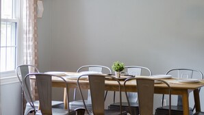 Een eettafel met zes stoelen, een potplant en een raam met gordijnen.