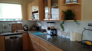 A kitchen with wooden cabinets, a stainless steel dishwasher, a coffee maker, and a plant on the counter. - ME MATES PLACE CLOSE TO THE BEST BEACHES THROUGH OUT THE ESPERANCE REGION,. (Condingup, ESPERANCE)