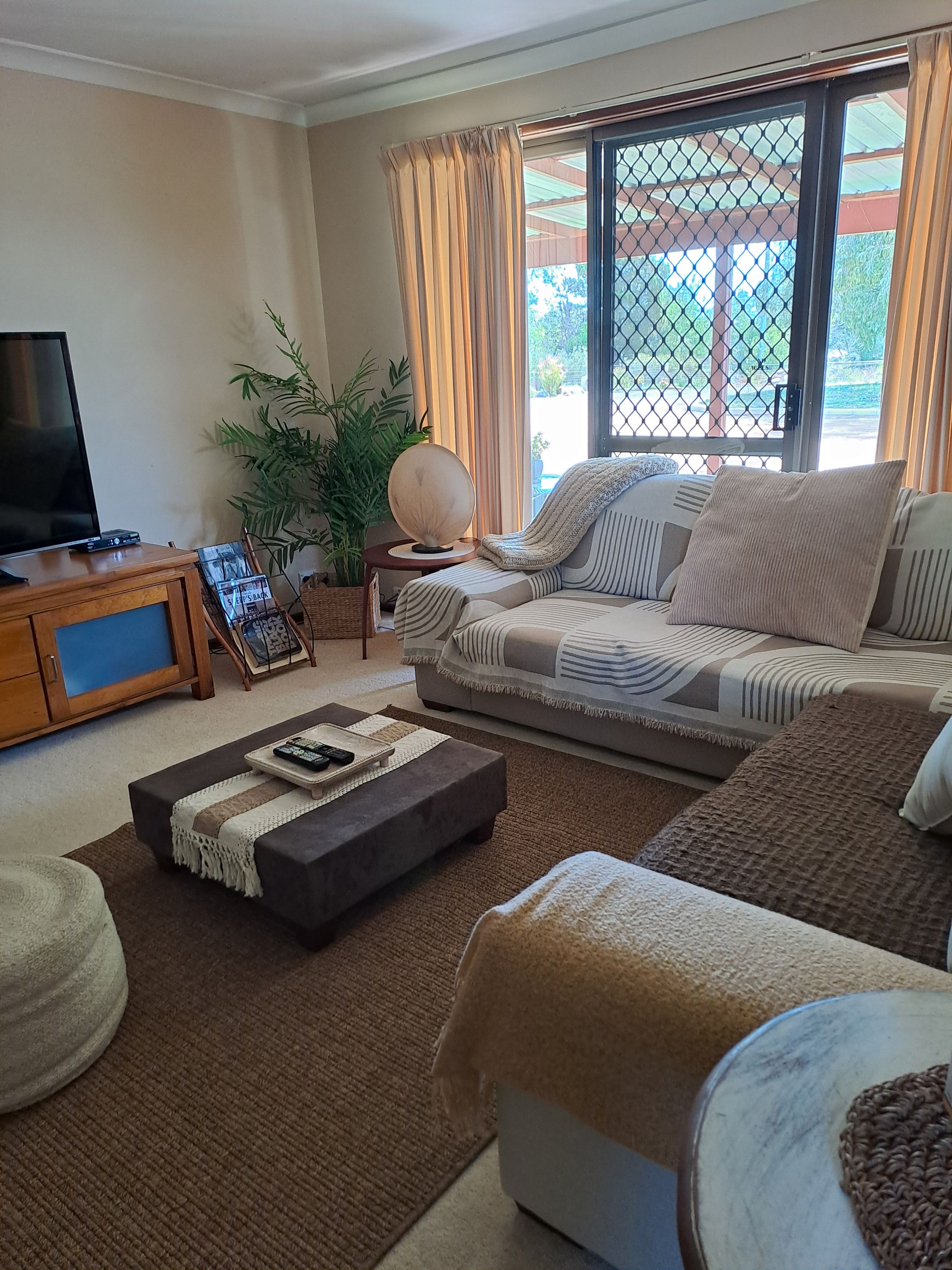 A living room with a sofa, ottoman, and a television on a wooden cabinet.
