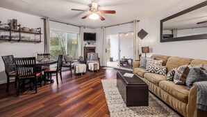 A spacious living room with a wooden floor, a ceiling fan, a large window, a sofa, and a dining area with chairs and a table. - 5 bedrooms. 2 Blocks to Barton Springs Pool, Zilker Park, Music, Food Trailers (Austin)