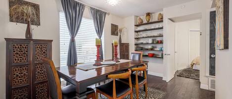 A dining area with a wooden table, four chairs, a decorative vase, and a patterned rug.