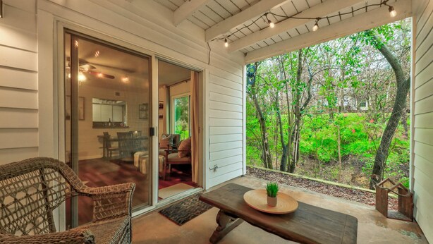 A covered patio with wicker furniture, a wooden table, and a view of a lush garden. - 5 bedrooms. 2 Blocks to Barton Springs Pool, Zilker Park, Music, Food Trailers (Austin)