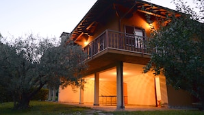 Un bâtiment à deux étages doté d’un balcon, d’un espace extérieur couvert et d’un jardin.