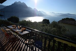 Une terrasse avec une table dressée pour le dîner, donnant sur un lac et offrant une vue sur des montagnes en arrière-plan.