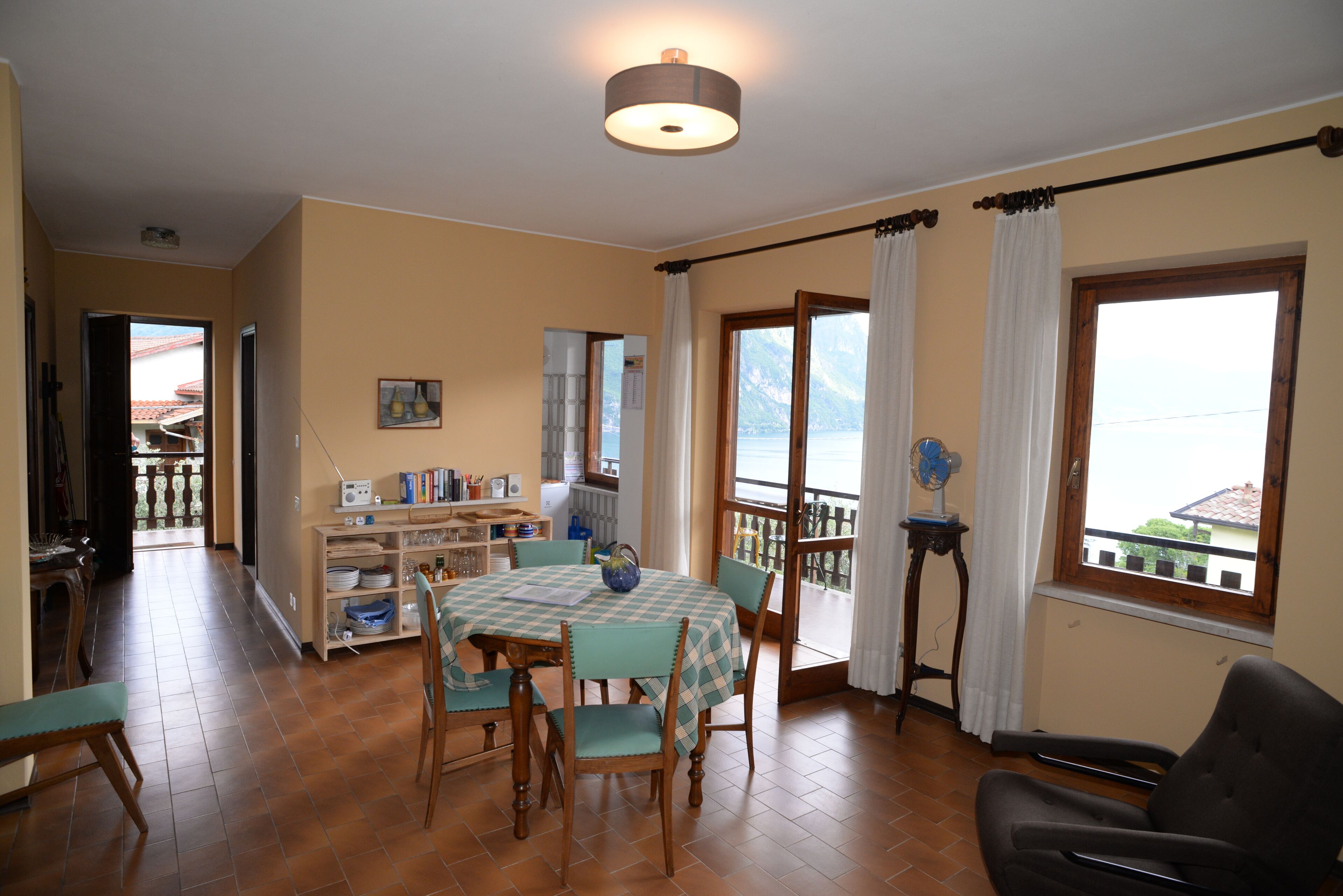 Un comedor con mesa y sillas, una cocina al fondo y vistas a través del ventanal.