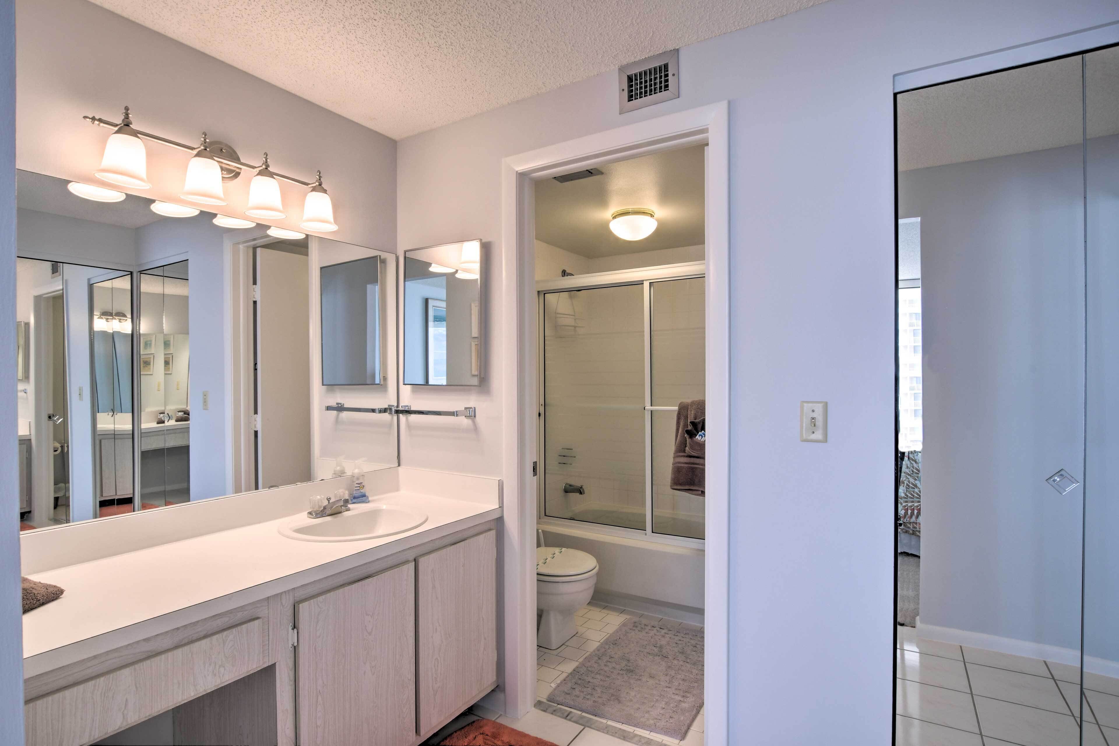 A modern bathroom with a large mirror, white vanity, and a glass shower enclosure.