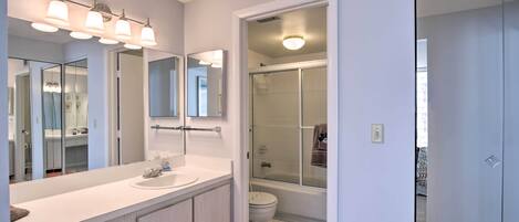 A modern bathroom with a large mirror, white vanity, and a glass shower enclosure.