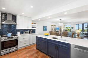 A modern kitchen with white cabinets, a blue backsplash, and a large island with a sink.