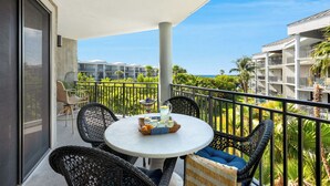 Een balkon met een ronde tafel, rieten stoelen en een dienblad met drankjes.