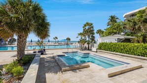 A pool area with multiple swimming pools, palm trees, and a building in the background. - ATLANTIC BREEZE ~ 2B/2BA Renovated Retreat w/ Pool, Fitness Area & Beach! (Key West)