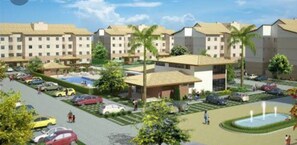 A hotel complex with multiple buildings, a parking lot, and a swimming pool. - Apartment in milionários beach, Ilheus - BA (Ilheus)