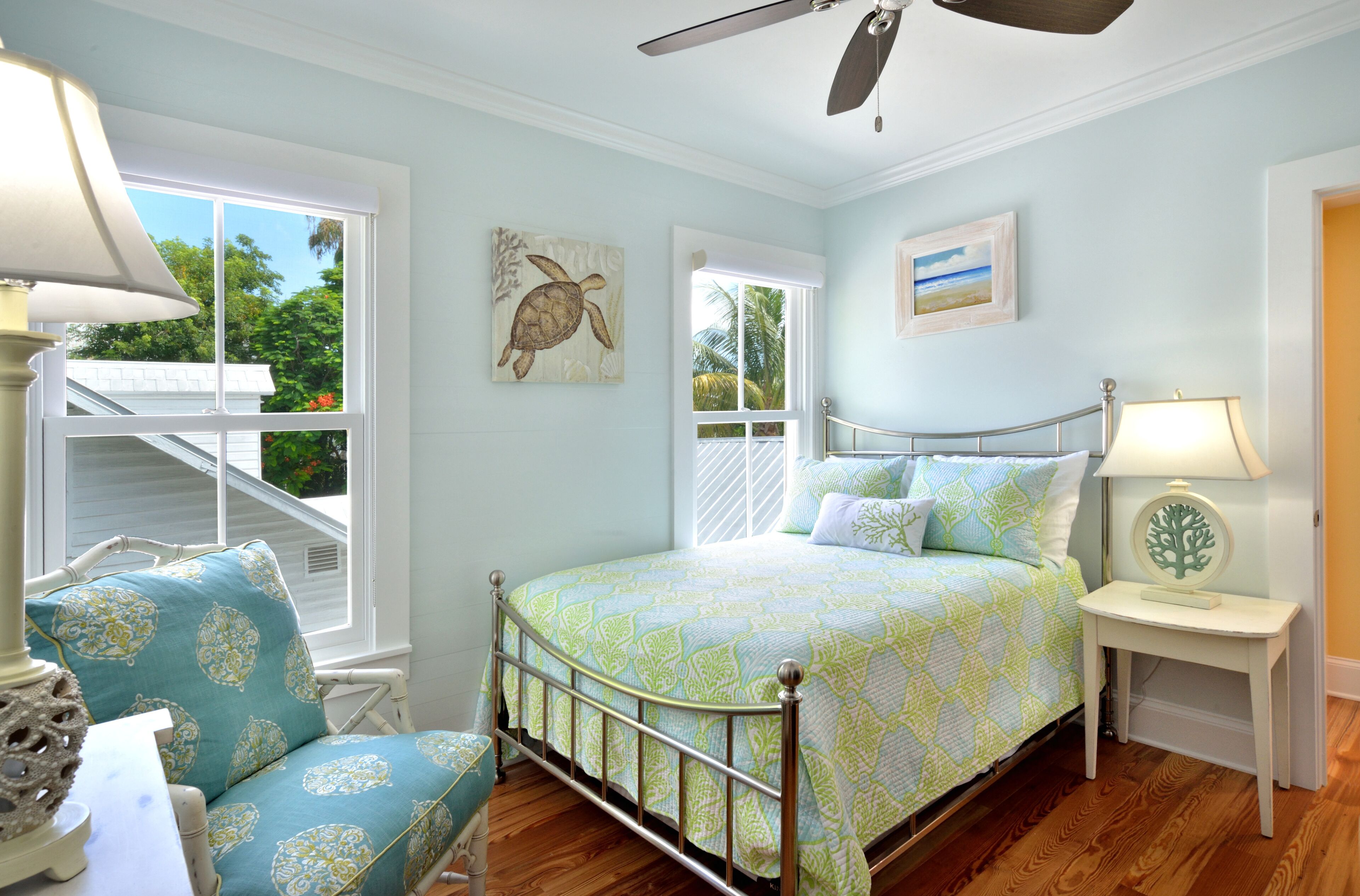 A bedroom with a bed, a chair, a nightstand, and a ceiling fan.