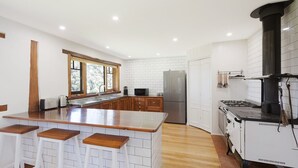 Eine moderne Küche mit Kochinsel, Holzbarhocker, eingebautem Herd und einem Edelstahlkühlschrank.