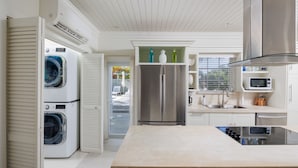 A modern kitchen with a central island, built-in appliances, and a view to the outdoors. - ONE PALM HILL - Luxury Villa with Private Pool, Walk to Twin Coves Beach (Governors Harbour)